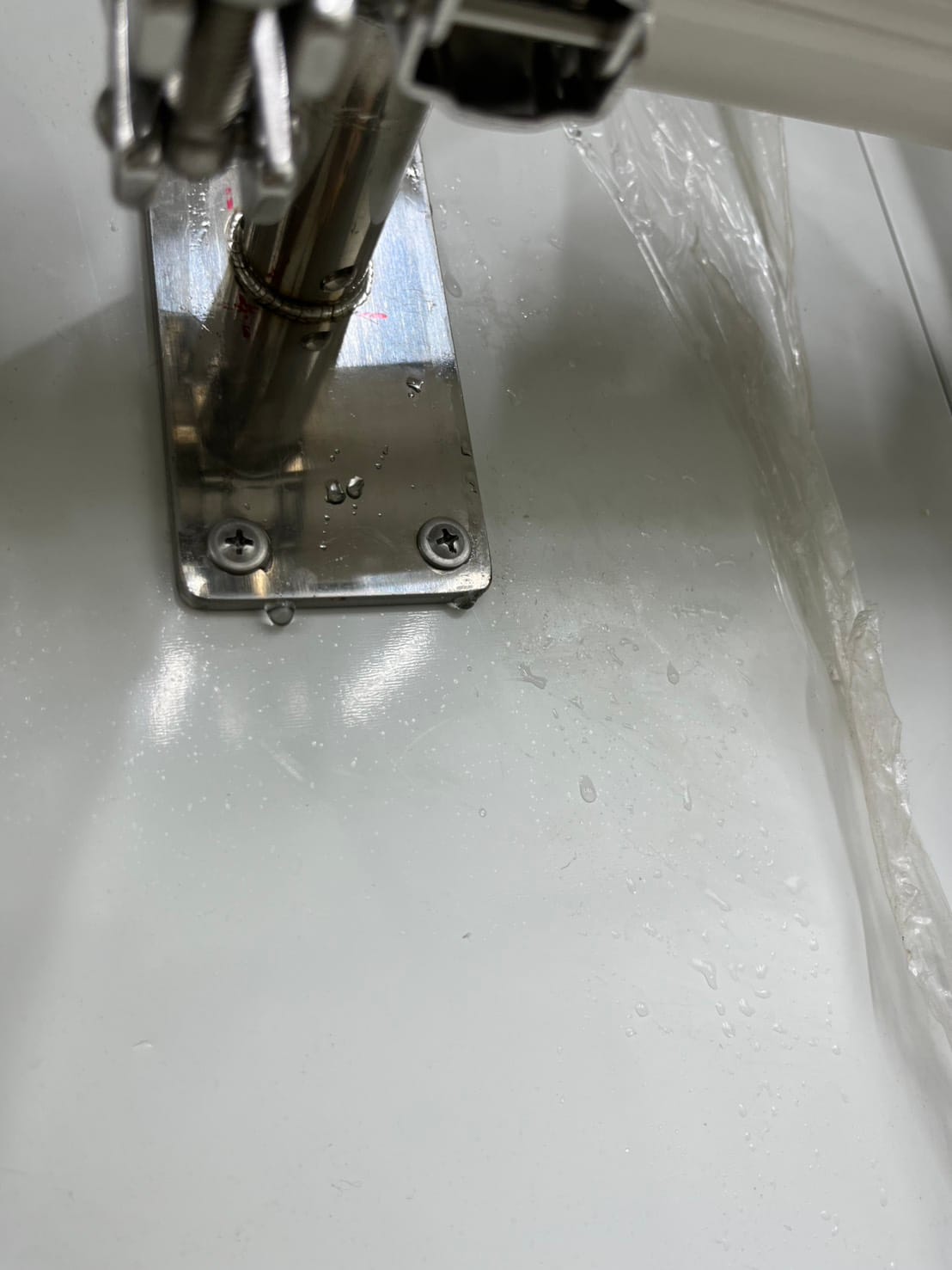 Liquid droplets on the support bracket and surface below the reported leaking installation.