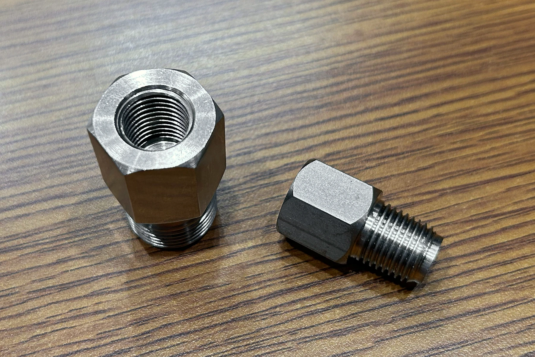 Two metal thread adapters showing internal and external threads