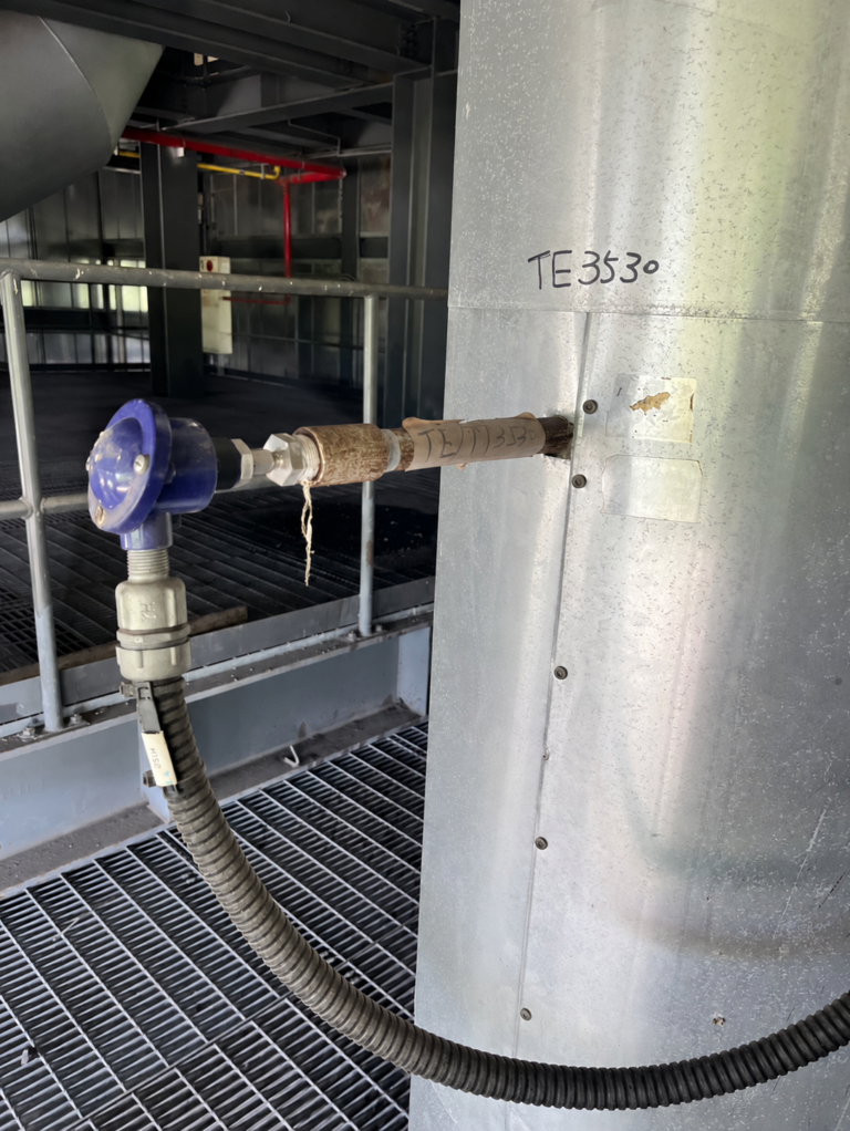 Temperature sensing assembly entering an insulated industrial pipe